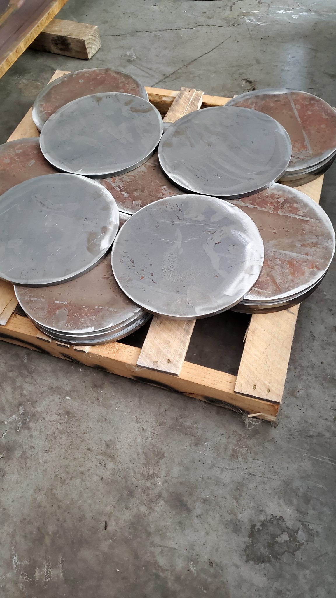 Stack of large circular metal discs ready for distribution from CMDI's fabrication floor.